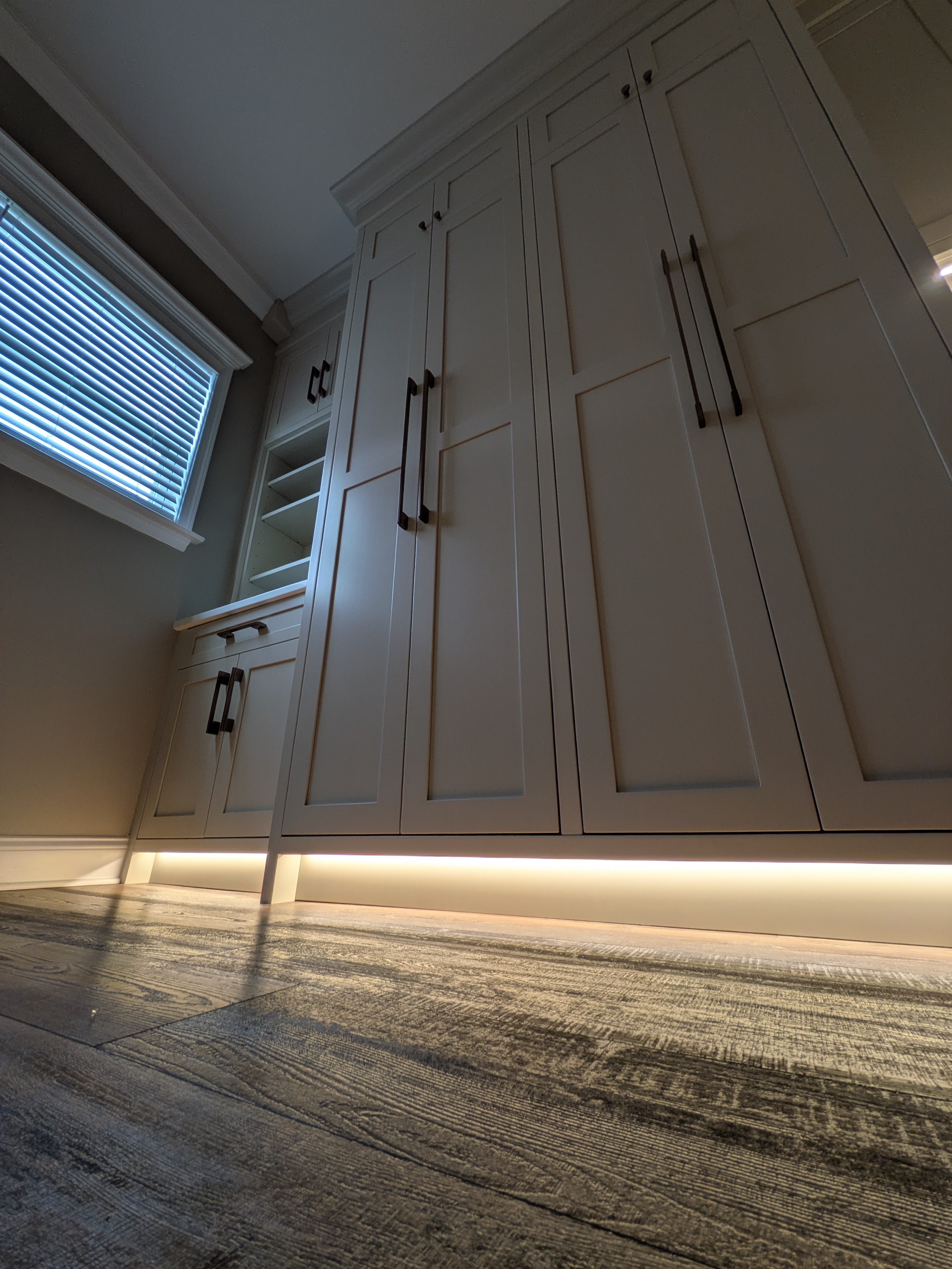 Mudroom cabinetry with ambient toe kick lighting at night